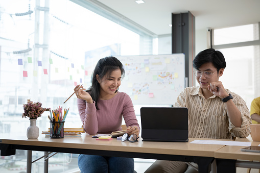 Two startup employee consulting with digital tablet in modern office.