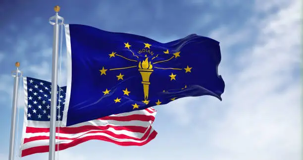 Photo of The Indiana state flag waving along with the national flag of the United States of America.