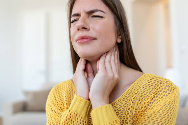 gros plan d’une jeune femme frottant ses amygdales enflammées, problème d’amygdalite, recadrée. femme avec un problème de glande thyroïde, touchant son cou, fille a mal à la gorge - pharyngitis photos et images de collection