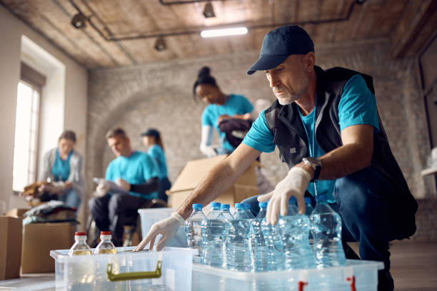 Mature volunteer organizing donations in boxes while working at humanitarian aid center.