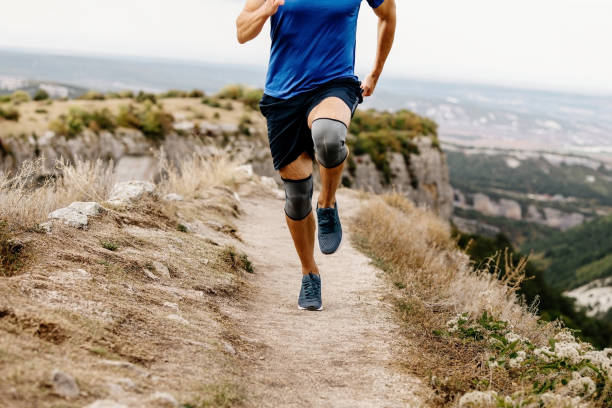 male runner running trail in knee pads male runner running trail in knee pads kneepad stock pictures, royalty-free photos & images