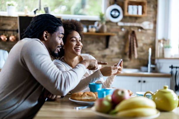 istock Happy black couple using cell phone during morning time at home. 1391579560