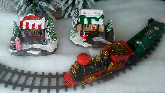 Christmas old-fashioned train toy on fake snow under Christmas tree. Winter scene.