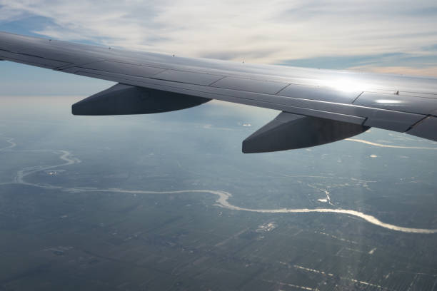 Wing of an airplane flying above Netherlands with view at river Lek