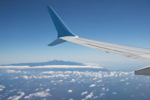 Wing of an airplane flying above Atlantic Ocean with view at island Tenerife with mount teide