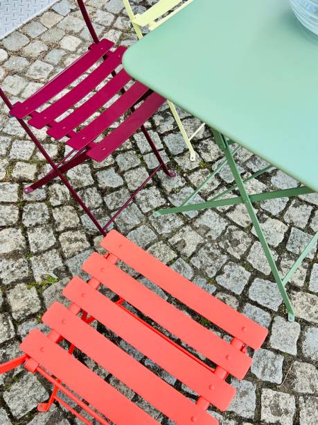 istock Dark red and light red chairs and a green table on a cobblestone road 1391581811