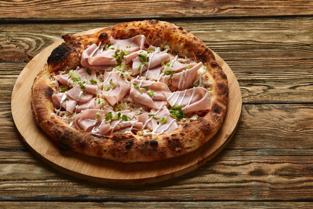 istock Fresh pizza with ham and pineapple on wooden table in restaurant 1391581919