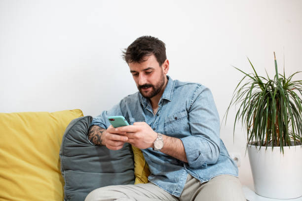 istock Handsome young man siting on the sofa and texting 1391582078