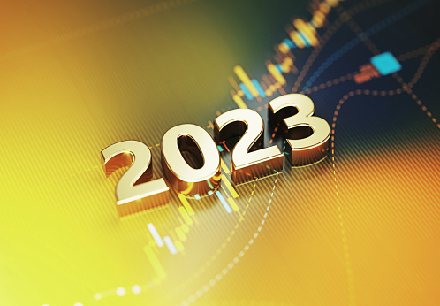Gold colored 2023 sitting on yellow financial graph background. Horizontal composition with selective focus and copy space. Investment, stock market data and finance concept.