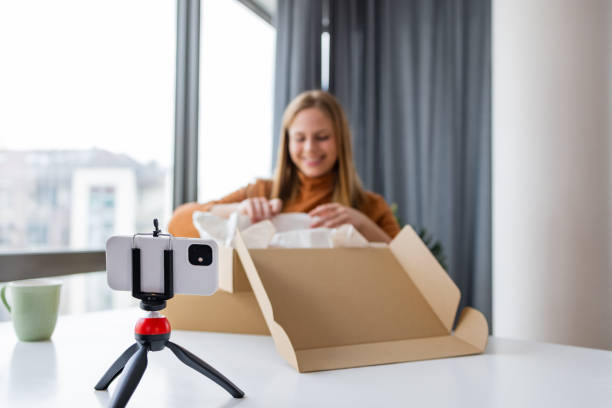 istock Woman vlogging from home while opening her online purchase 1391583408