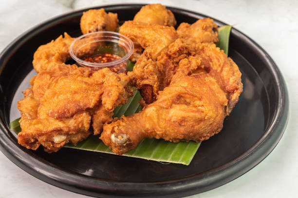 istock Appetizing fried chicken that sits on a banana leaf in a black plate. 1391583624