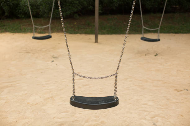 istock Swing set seat hanging on metal chains at a playground. 1391583635