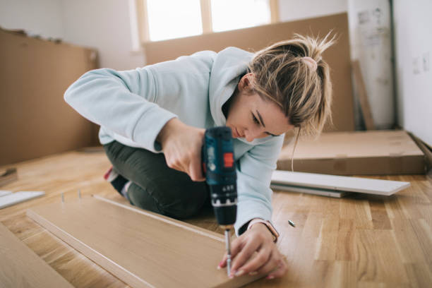 Woman assembling furniture at home stock photo