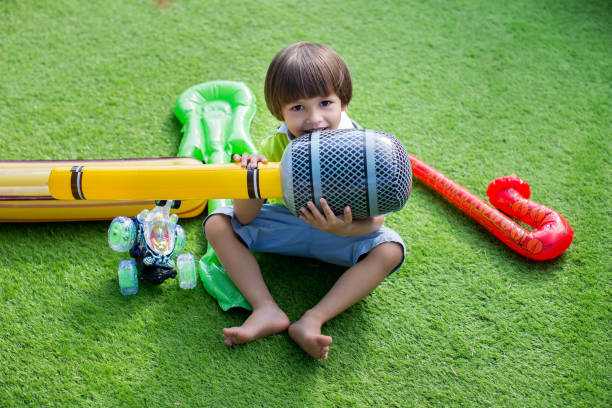 Young boy happily playing in a sandbox, holding a shovel and rake, enjoying the outdoors and embracing imaginative adventures