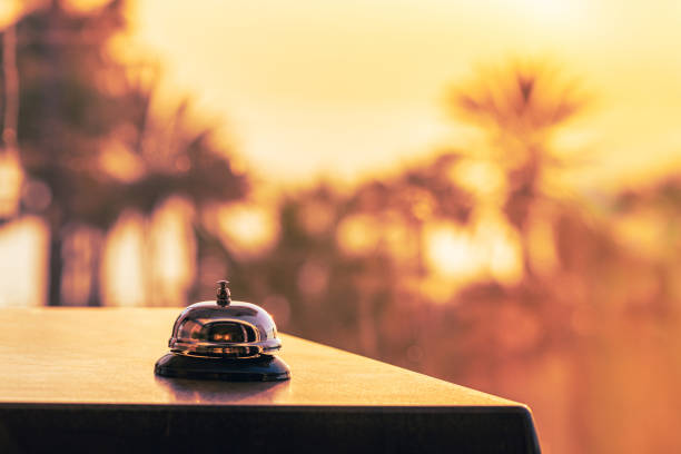 Beach hotel service bell against the background of coastline sea and palm tree on sunset. Travel concept. 24-hour hotel front desk. Late check-out. Beach hotel service bell against the background of coastline sea and palm tree on sunset. Travel concept. 24-hour hotel front desk. Late check-out. airport check in counter stock pictures, royalty-free photos & images