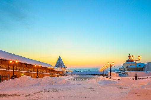The courtyard covered with snow, the fortress wall and the watchtower of the Kazan Kremlin against the sunset