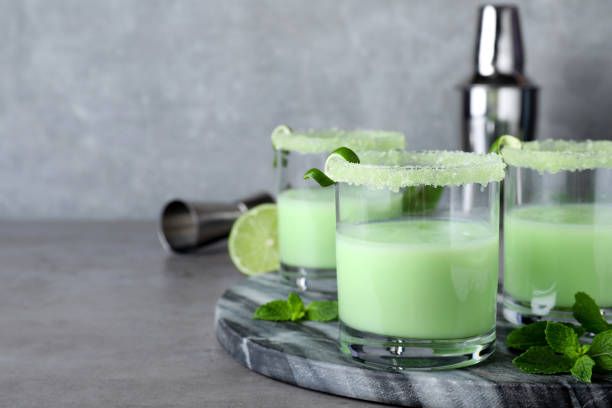 istock Delicious mint liqueur with ice cubes and green leaves on grey table. Space for text 1391590132