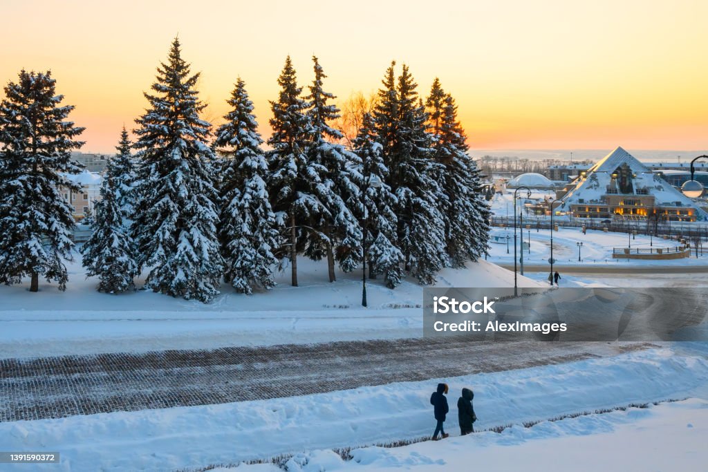 snow-covered trees and modern buildings Winter city landscape, snow-covered trees and modern buildings against the sunset background. Winter Stock Photo