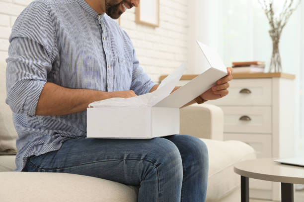 istock Man unpacking parcel at home, closeup. Online shopping 1391590610