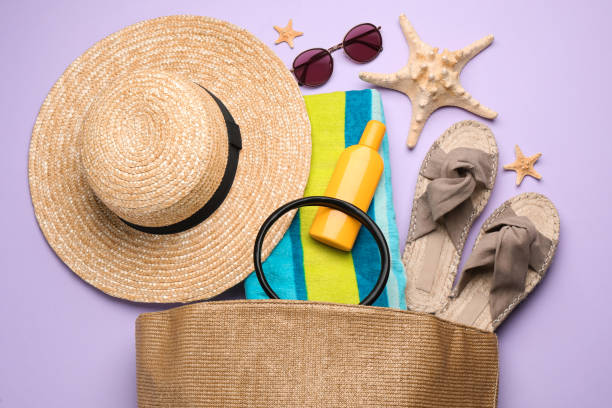 istock Stylish bag with beach accessories on violet background, flat lay 1391590641