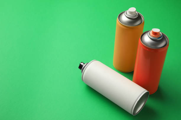 istock Cans of different spray paints on green background, space for text. Graffiti supplies 1391590725