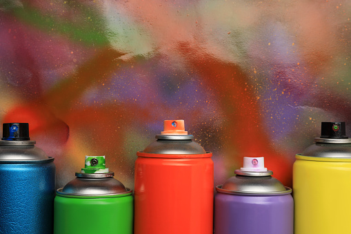 Cans of different graffiti spray paints on color background, flat lay. Space for text