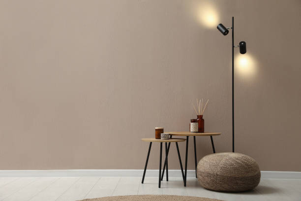 istock Knitted pouf, lamp and decor elements near beige wall indoors. Space for text 1391590826