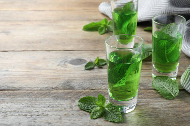 istock Delicious mint liqueur with green leaves on wooden table. Space for text 1391591400