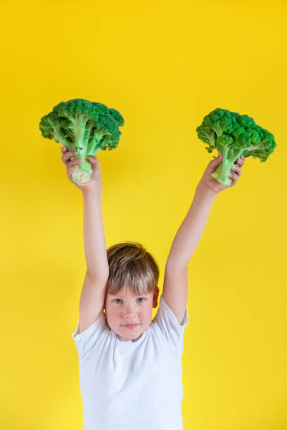 istock Adorable boy with broccoli on color background 1391591933