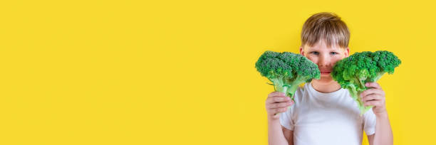istock Adorable boy with broccoli on color background 1391591936