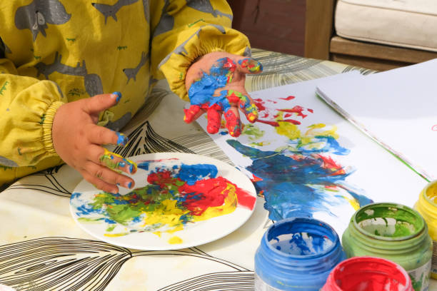 Early childhood development activity: finger painting outside on a sunny day