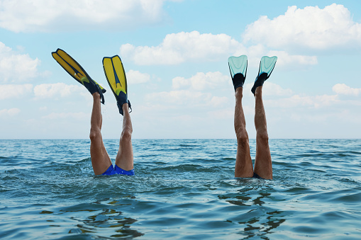Hombres con aletas buceando en el agua de mar photo