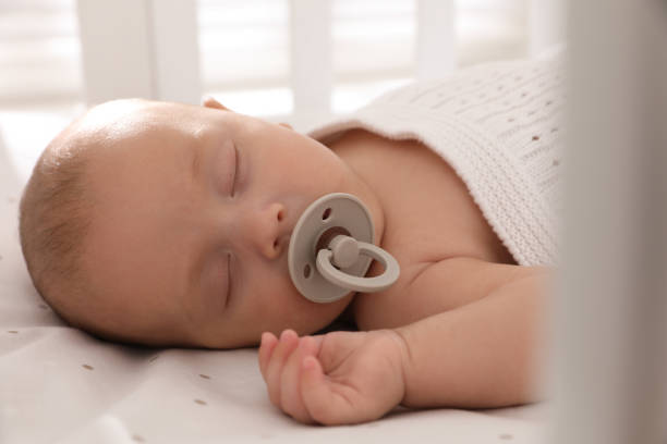 istock Cute little baby with pacifier sleeping in crib, closeup 1391595089