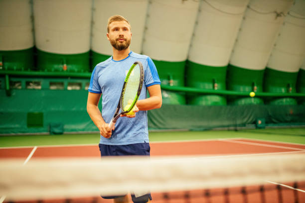 инструктор или тренер учит играть в теннис на корте в помещении - tennis men indoors playing стоковые фото и изображения