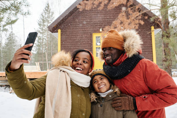 feliz familia de tres posando para selfie en el país en un día nevado de invierno - telephone cabin fotografías e imágenes de stock