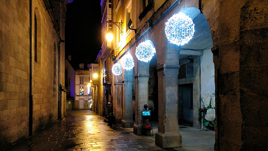 Modern lighting Christmas white spheres decorations, close-up of Lugo city cathedral,narrow street, arcade, Galicia, Spain.