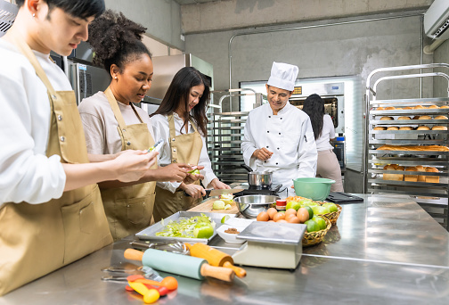 Students In Cookery Class Mixing Ingredients For Recipe In Kitchen.Group of young people taking selfie during cooking classes.