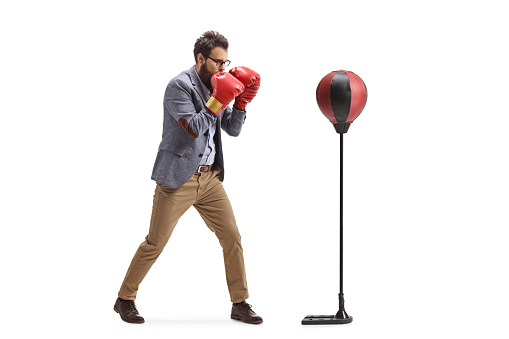 Man in formal clothes punching a free standing boxing bag isolated on white background