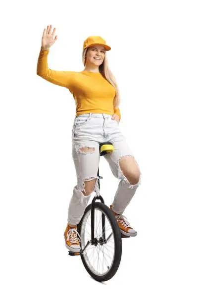 Young female on a unicycle waving at camera isolated on white background