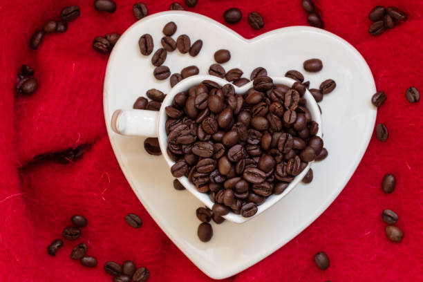 istock Heart shaped cup with coffee beans on red 1391605425