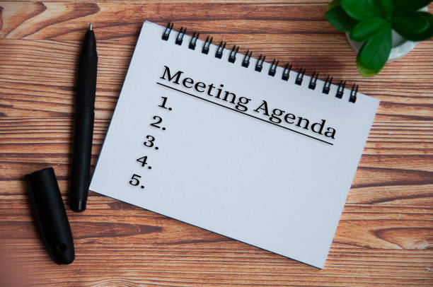 istock Meeting agenda text on notepad with plant, pen and wooden table background. 1391612937