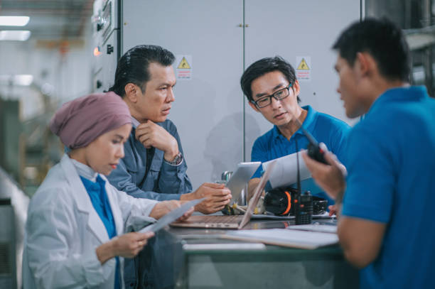 manajer pabrik asia bertemu dengan diskusi pekerja lini produksi tentang kemajuan produksi di lini produksi pabrik air minum dalam rutinitas sehari-hari - engineering potret stok, foto, & gambar bebas royalti
