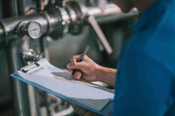 istock Asian Chinese technician recording meter reading in tank routine quality control in water bottling factory writing on clipboard 1391619716