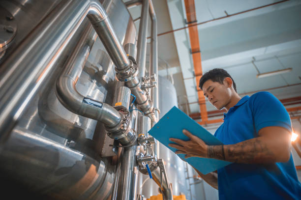 istock Asian Chinese technician recording meter reading in tank routine quality control in water bottling factory writing on clipboard 1391619724