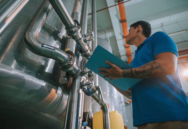 istock Asian Chinese technician recording meter reading in tank routine quality control in water bottling factory writing on clipboard 1391619726