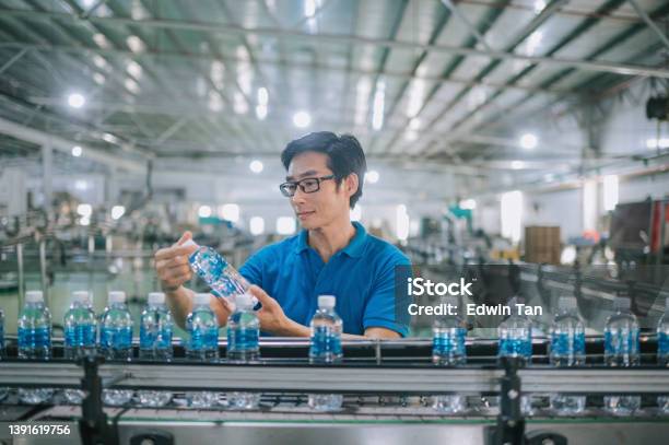 Asian Chinese Male Production Line Worker Examining Water Bottle In Bottling Plant Mineral Water Drinking Water Factory Stock Photo - Download Image Now