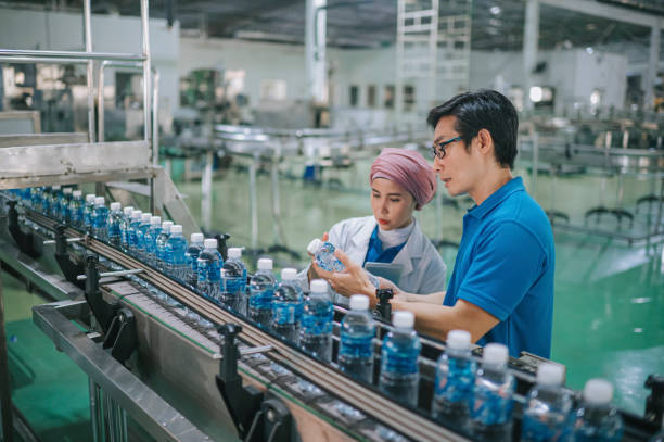 азиатский малайский инспектор проверяет качество минеральной воды на заводе по производству минеральной воды - water bottle plastic bottle bottling plant стоковые фото и изображ�ения