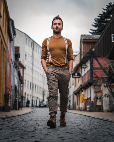 Confident man in vintage clothing walking down a street