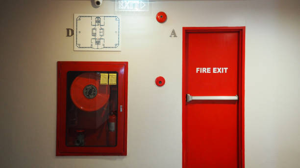 istock Fire exit door. Fire exit emergency door red color metal material with alarm and emergency light and fire extinguish equipment on building wall for safety protection. Doors for escape conflagration. 1391625011