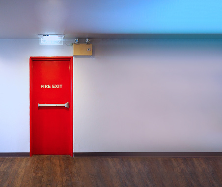 Fire exit door. Fire exit emergency door red color metal material with alarm and emergency light and fire extinguish equipment on building wall for safety protection. Doors for escape conflagration.